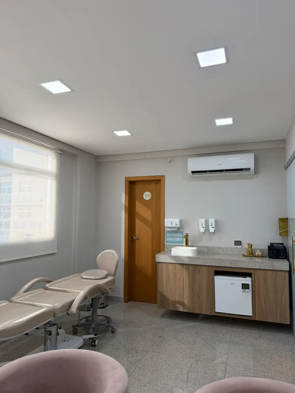 Sala de procedimentos com maca, bancada e janela ampla